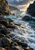 A small white seabird on a wet rock at left, amid dark cliffs, foaming teal water and a bright cove opening.