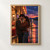 Two adults embrace beneath a glowing roadside diner canopy beside a wet highway at dusk.; frame shown for styling only