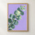 Diagonal eucalyptus branch with rounded blue-green leaves and a small new pair against a lilac background.; frame shown for styling only