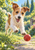 Scruffy tan-and-white terrier leaping toward a red ball on a garden path, with sunlit green foliage behind.