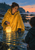 A woman in a saffron-yellow cape holds a glowing lantern above tidal water at dusk as a dark figure stands at the right edge.