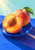 A cut peach with exposed pit, a whole peach and green leaf on a cobalt-blue plate in diagonal sunlight.