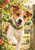 Tan-and-white terrier wearing a green scarf and reaching forward between orchard gate posts, with apples and leaves.