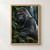 Close portrait of a silverback gorilla with one hand on a stone ledge, framed by glossy leaves in a shadowy rainforest.; frame shown for styling only