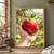 A red apple with a dew bead and two green leaves is held in an open hand against a softly blurred orchard background.; frame shown for styling only