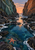 A coral-colored starfish in a blue-green tide pool beneath a peach sunset framed by tall rocky cliffs.