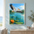 White pelican with spread wings and trailing feet flying above turquoise lagoon ripples, with reeds, lily pads, and an orange water lily.; frame shown for styling only
