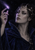 Fantasy woman in a silver circlet and dark high-collared garment studying a glowing violet comet above her raised fingers.