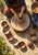 Overhead view of a craftsperson shaping a tall vessel on a pottery wheel among finished bowls and rough clay forms.