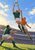 Three rugby players in green and orange kits contest an airborne oval ball beneath a bright stadium sky.