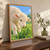 Close portrait of a cream-white lamb bending to nibble clover in a green meadow under blue sky.; frame shown for styling only