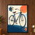 Antique-style navy bicycle with brass headlamp and two circular mechanical detail insets against a coral and ivory background.; frame shown for styling only