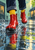 Glossy cherry-red ankle rain boots and yellow socks stepping through a city puddle, with water splashes and colorful reflections.