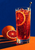 A tall glass of ruby-red sparkling citrus drink with an orange wheel and swizzle spoon, beside whole and cut oranges against a deep blue background.
