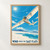 White glider with a seated pilot banking above pale salt flats and a turquoise pool, with mountains and title lettering below.; frame shown for styling only
