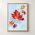 Five red, orange, and plum maple-shaped leaves float diagonally against pale blue, with fine veins and scattered winged seed forms.; frame shown for styling only
