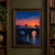 Small silhouetted cyclist with an amber light on a stone bridge, with a lighthouse and sunset beyond.; frame shown for styling only