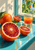 Cut blood oranges and a glass of orange juice on a turquoise windowsill beside an open window with citrus leaves.
