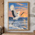 Red-crowned crane taking flight above snowy tidal water, with pine islands and an apricot-and-blue dawn sky.; frame shown for styling only