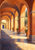Painterly terracotta arches recede along a covered walkway toward a blue doorway, with sunlight and potted greenery.