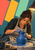 Woman potter shaping a cobalt-blue vessel on a wheel beneath a task lamp, with coral, saffron, and mint color panels.