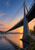 Cable-stayed bridge with a tall pylon and sweeping cables over a misty river at dawn.