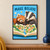 A red panda and badger lean over an open book showing a tiny village beneath paper stars and the heading MAKE BELIEVE.; frame shown for styling only