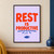Bold vermilion “REST IS PRODUCTIVE” lettering on pale lilac, with a blue sunbeam underline and closed book icon.; frame shown for styling only