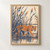 Tawny lioness walking among angular blue and rust reeds above reflective water on a warm ivory background.; frame shown for styling only