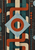 Geometric woven pattern with a pale-blue central diamond crossed by a rust ring, surrounded by interlocking bands and dotted columns.