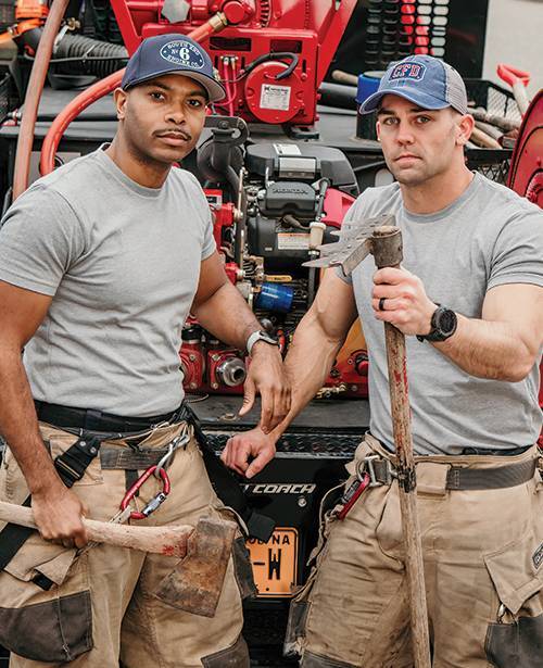 Two firefighters with custom embroidered beanies near fire truck