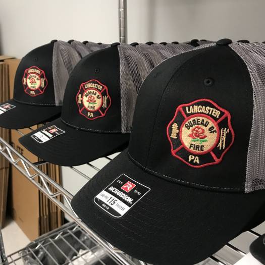 Custom embroidered fire department hats on a shelf