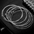 Coiled nickel wound and steel electric guitar strings with ball ends resting on a black electric guitar body.
