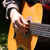 Close-up of a classical guitar being played, showing nylon strings, fretboard and sound hole rosette details
