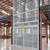 Four-post vertical reciprocating conveyor with safety enclosure for heavy-duty pallet and equipment handling