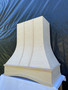 Unfinished maple curved wood range hood with decorative vertical wood accents and arched apron, designed as a focal point for a custom kitchen remodel