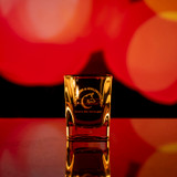 Wholesale engraved 2 oz. Prism Shot Glass customized with Copper Fox Distillers logo on a bokeh background