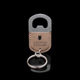 Wholesale engraved Oval Tan Keychain Bottle Opener customized with Cathead Distillery logo on a black background
