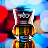 Wholesale engraved 9 oz. Urban Bar Thistle Old Fashioned Glass customized with Thistle Finch Distilling logo on a bokeh background