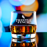 Wholesale engraved Scirocco Rocks Glass customized with Thistle Finch Distilling logo on a bokeh background