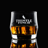 Wholesale engraved Scirocco Rocks Glass customized with Thistle Finch Distilling logo on a black background