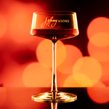 Wholesale engraved 9.25 oz. Stolzle Power Coupe customized with J Henry & Sons logo on a bokeh background