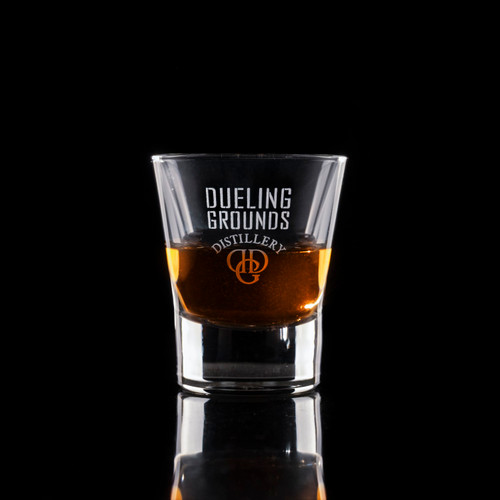 Wholesale engraved 2.25 oz. V Shot Glass customized with Dueling Grounds Distillers logo on a black background