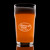 Wholesale engraved 20 oz. English Nonic Pub Glass customized with Cabbage Shed logo on a black background