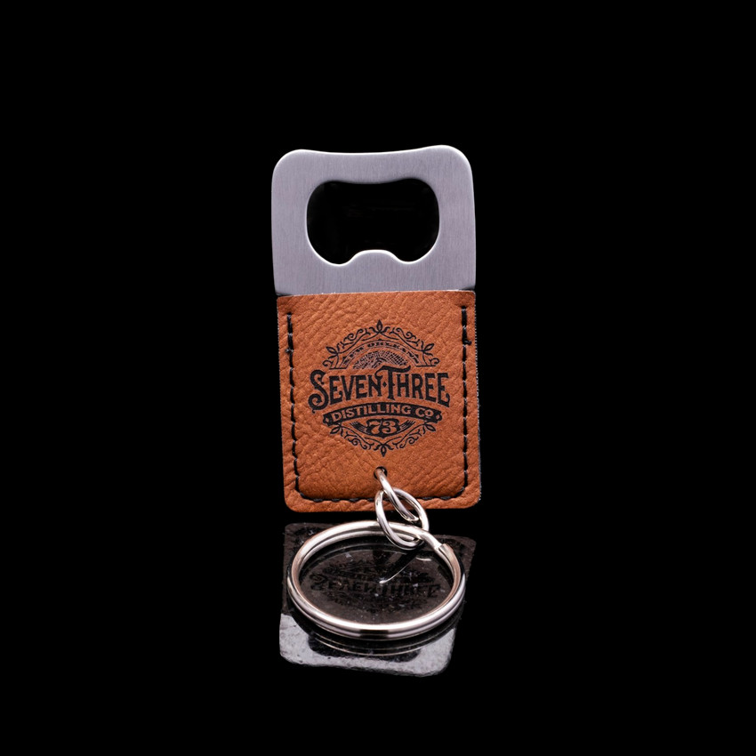 Wholesale engraved Square Cognac Keychain Bottle Opener customized with Seven Three Distillery logo on a black background