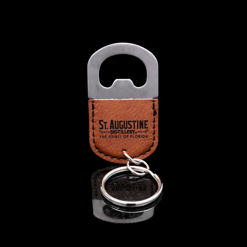 Wholesale engraved Oval Cognac Keychain Bottle Opener customized with St Augustine Distillery logo on a black background