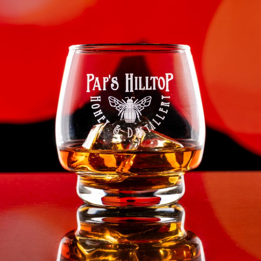 Wholesale engraved 10 oz. Single Barrel Select Rocks Glass customized with Paps Hilltop Distillery logo on a bokeh background