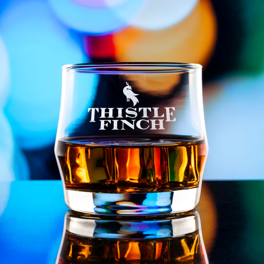 Wholesale engraved Scirocco Rocks Glass customized with Thistle Finch Distilling logo on a bokeh background