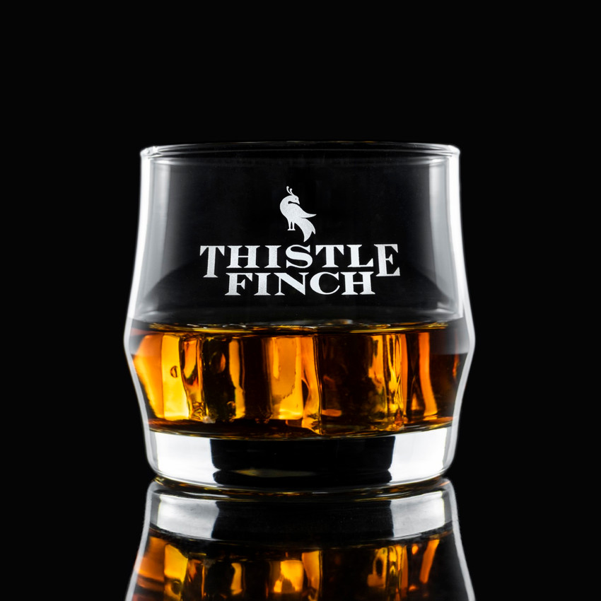 Wholesale engraved Scirocco Rocks Glass customized with Thistle Finch Distilling logo on a black background