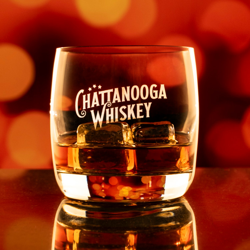 Wholesale engraved 10.5 oz. Nordic Nuevo Rocks Glass customized with Chattanooga Whiskey logo on a bokeh background